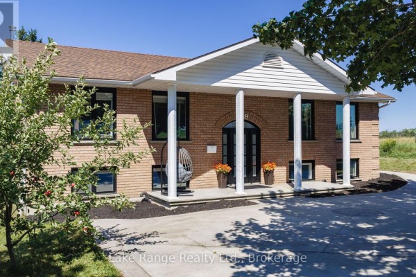 Side view of the brick house exterior with trees and green landscaping. - 349 South Delhi Street, Huron Kinloss