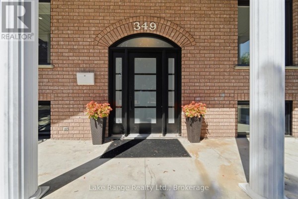 Double glass doors at the entrance of the brick house, flanked by potted plants. - 349 South Delhi Street, Huron Kinloss