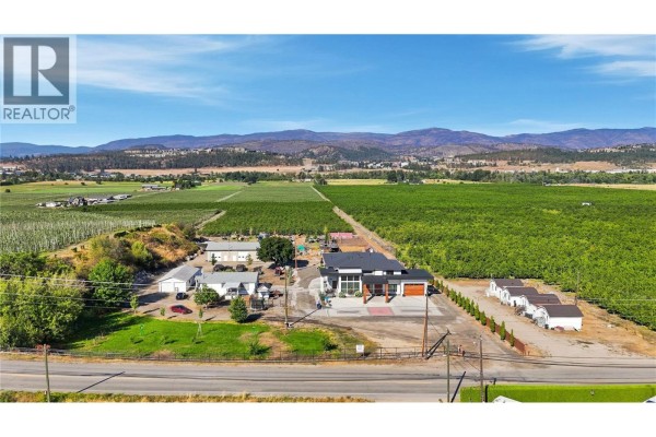 Wide aerial view of the property showing the main house, outbuildings, and extensive orchards. - 3490 Old Vernon Road, Kelowna