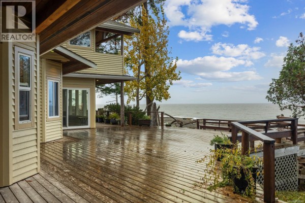 Exterior view of the house with a large deck overlooking the water. - 3495 Harwood Rd, Hornby Island