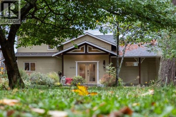 Front view of the house surrounded by greenery and autumn foliage. - 3495 Harwood Rd, Hornby Island