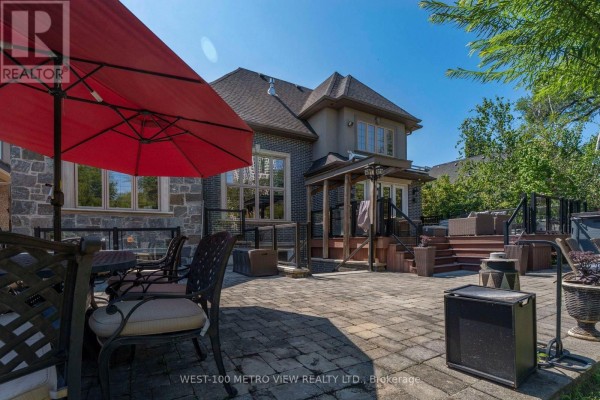 Backyard patio with brick pavers, outdoor furniture, a red umbrella, and a multi-level deck. - 3495 Joan Drive, Mississauga