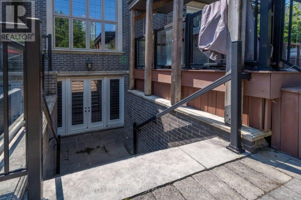 Exterior staircase leading down to a double door entrance with a brick wall and glass railings. - 3495 Joan Drive, Mississauga
