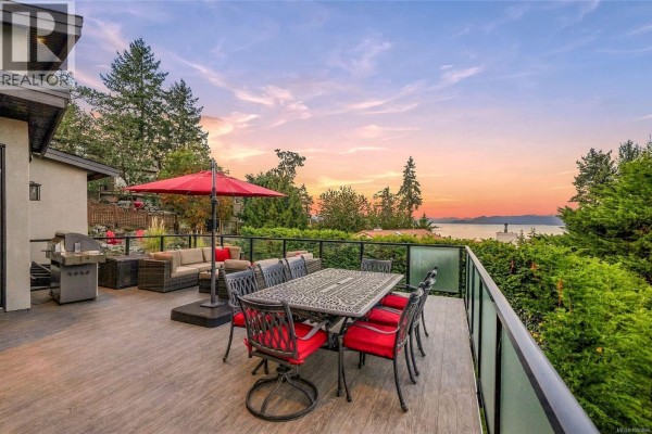 Deck with outdoor dining set and view of the water at sunset. - 3495 Simmons Pl, Nanoose Bay