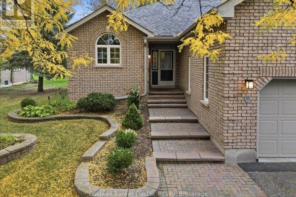 Close-up of the townhouse entrance with a brick pathway, stone retaining walls, and fall foliage. - 35 - 300 Franmor Drive, Peterborough
