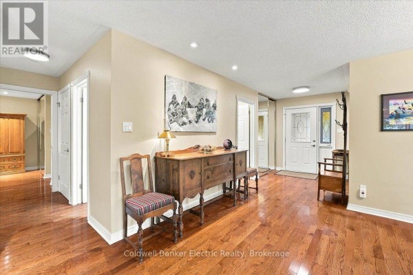 Interior hallway with hardwood floors, beige walls, antique furniture, and doors leading to other rooms. - 35 - 300 Franmor Drive, Peterborough