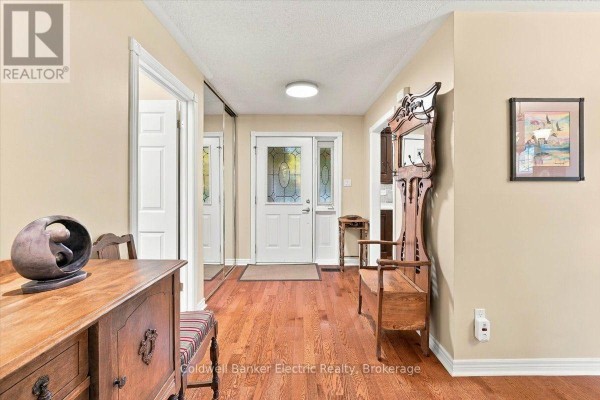 View of the entryway from the side, featuring hardwood floors, a mirrored closet, and antique bench. - 35 - 300 Franmor Drive, Peterborough