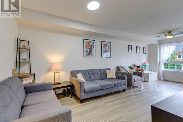 Living room with gray sofas, wood-look flooring, and a window with curtains. - 35 - 5260 Mcfarren Boulevard, Mississauga