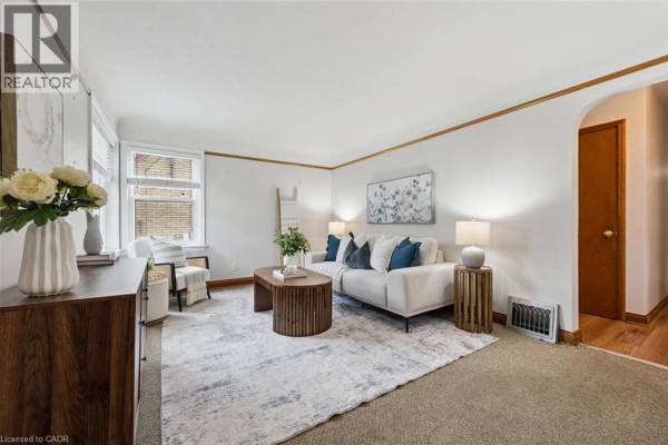 Living room featuring a sofa, coffee table, and a wooden sideboard against a white wall. - 35 Acacia Street, Kitchener