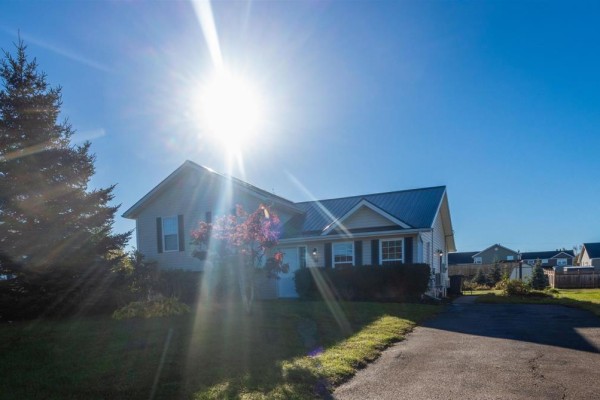 Front view of a beige house with a dark metal roof and bright sunlight. - 35 Barbour Circle, Charlottetown