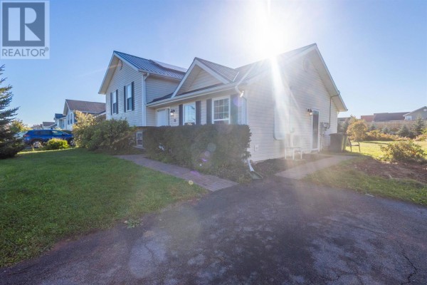 Side exterior of a beige house with a dark metal roof on a sunny day. - 35 Barbour Circle, Charlottetown