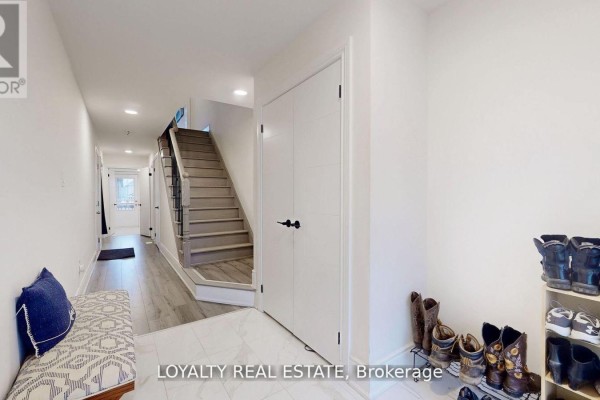 Spacious hallway with stairs leading to upper levels, bench seating, and shoe storage. - 35 Bavin Street, Clarington