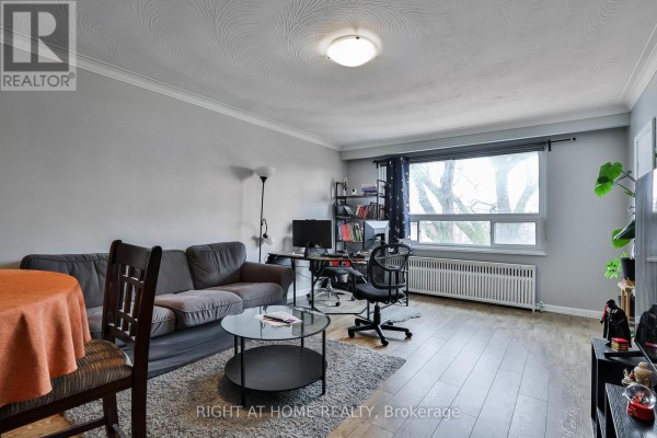 Living room with gray walls, hardwood floors, a gray sofa, and a large window with a view of trees. - 35 Fifteenth Street, Toronto