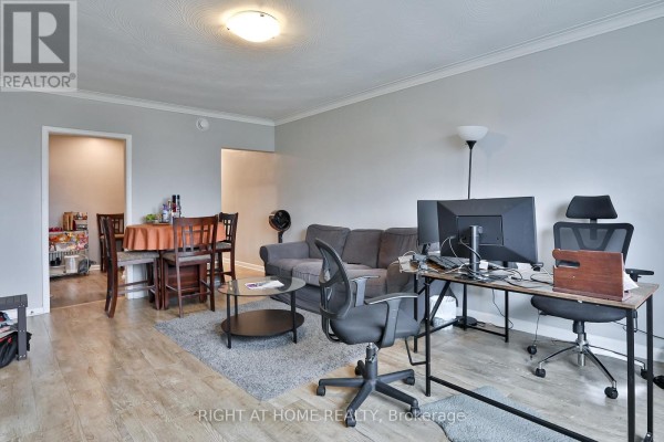 Living and dining area with gray walls, hardwood floors, a gray sofa, dining table, and desk. - 35 Fifteenth Street, Toronto