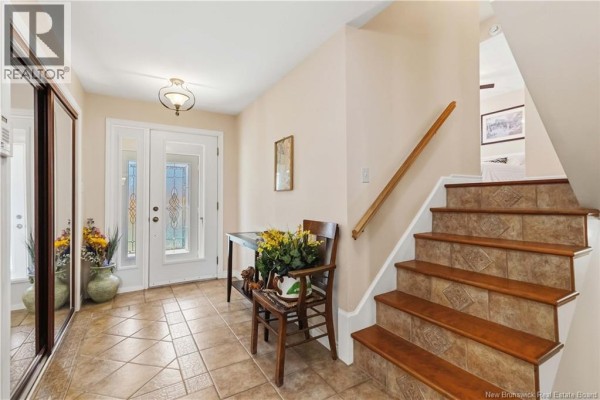 Backyard view of a house with a garden pond, sunroom, and attached garage. - 35 Firwood Crescent, Moncton