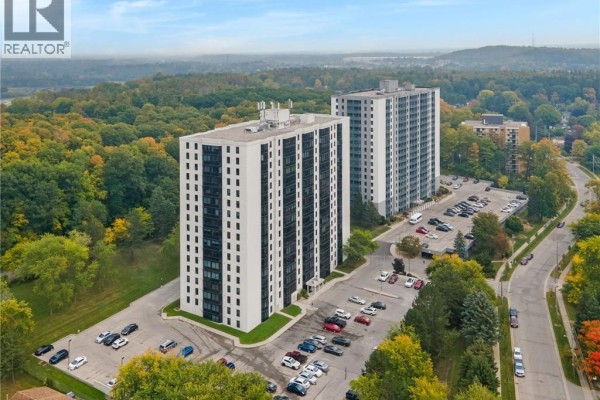 Aerial view of two white apartment buildings with parking lots on a tree-lined street. - 35 Green Valley Drive Unit# 308, Kitchener