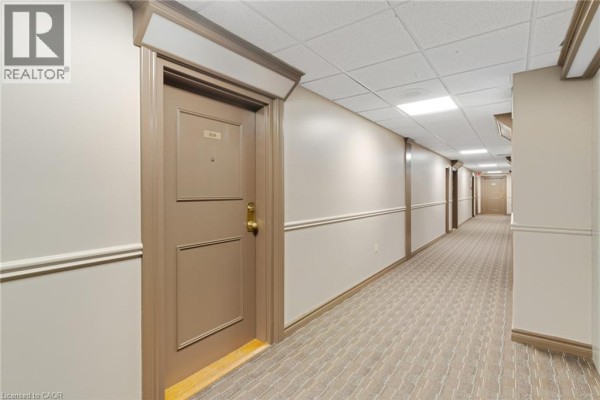 A long, carpeted hallway with beige walls and multiple apartment doors, including unit 308. - 35 Green Valley Drive Unit# 308, Kitchener