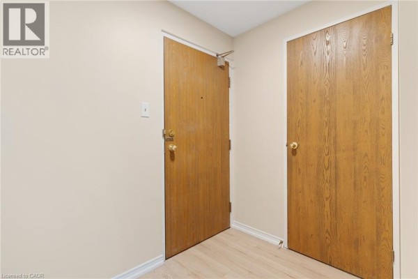 The interior entrance of unit 308 with two wooden doors and light wood laminate flooring. - 35 Green Valley Drive Unit# 308, Kitchener