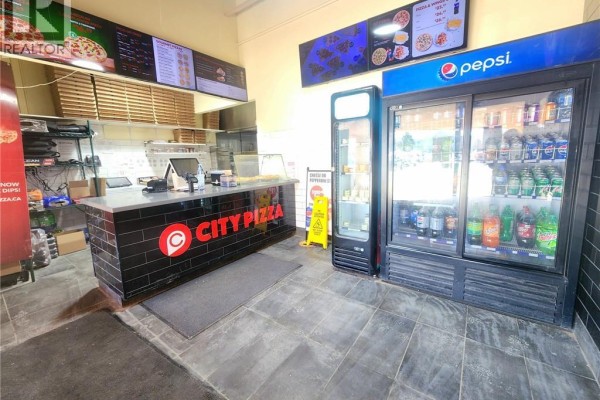 Interior view of a pizza restaurant showing the counter, cash register, pizza boxes, and two large drink coolers. - 35 Harvard Road Unit# 10, Guelph