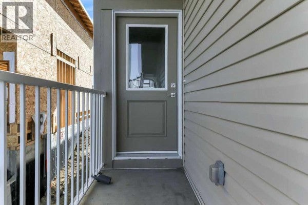 View of the side exterior of the duplex showing a grey door with a glass panel and white railing. - 35 Linden Place, Rural Red Deer County