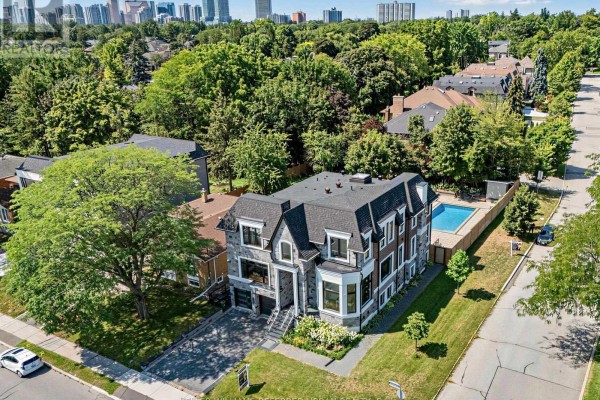 Aerial view of a large house with a dark roof, swimming pool, and surrounding trees. - 35 Lloydminster Crescent, Toronto