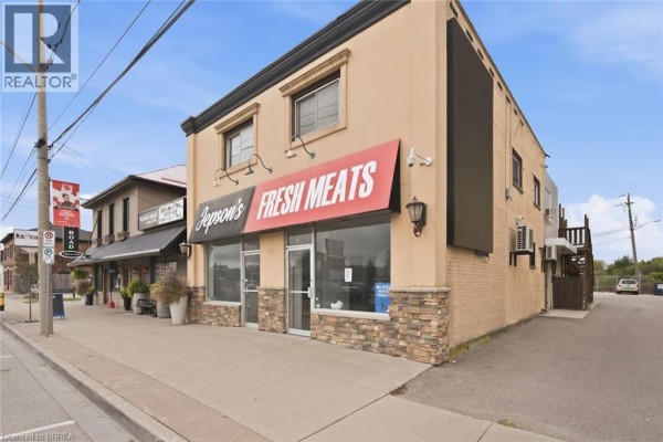 Side view of commercial building with tan facade, red and black awning, and brick side. - 35 Main Street N, Hagersville