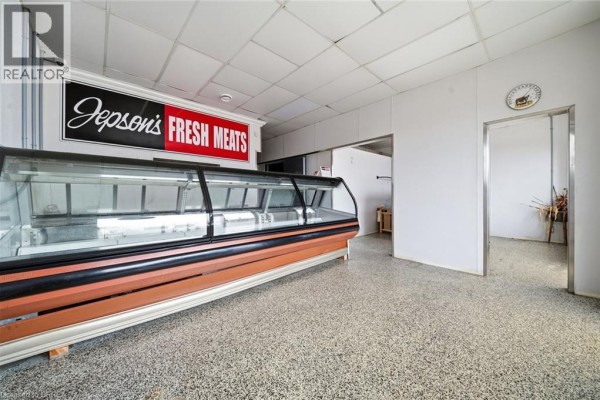 Interior view of empty commercial space with refrigerated display case and doorway. - 35 Main Street N, Hagersville