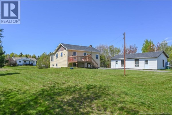 Kitchen with dark wood cabinets, granite island, stainless steel appliances, and a white door leading outside. - 35 Mallet Street, Haut Shippagan