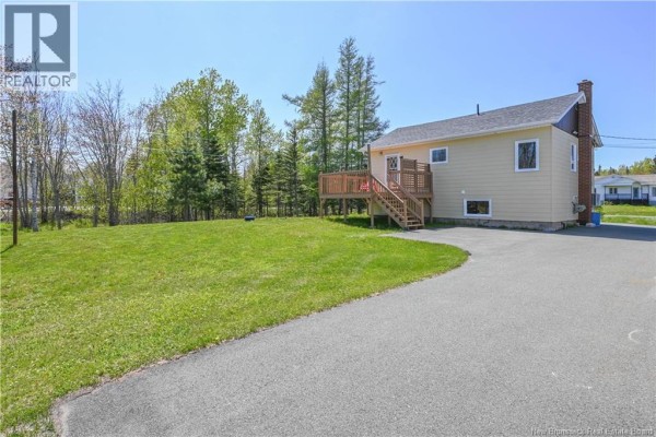 Dining space with windows overlooking trees, a light wood table and chairs, and a pass-through to another room. - 35 Mallet Street, Haut Shippagan