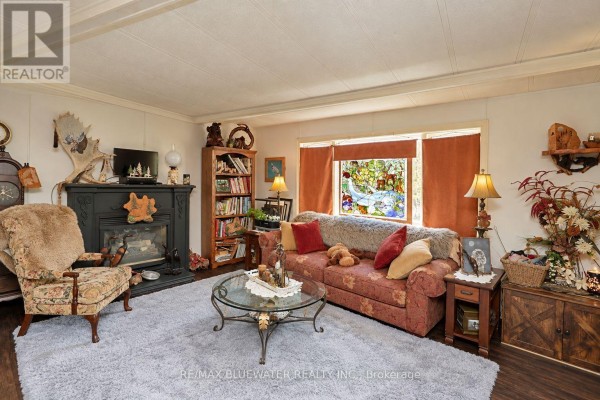 Living room with a floral sofa, glass coffee table, and a glass-front cabinet. - 35 Pebble Beach Parkway, South Huron