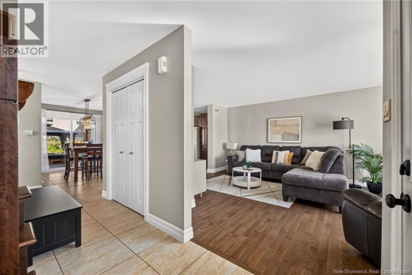 Living room with a sectional sofa, coffee table, and view into the dining area. - 35 Ruby Way, Moncton