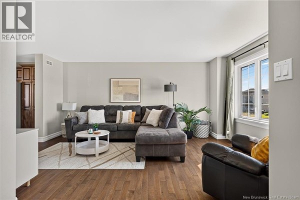 Living room featuring a dark gray sectional sofa, white coffee table, and hardwood floors. - 35 Ruby Way, Moncton