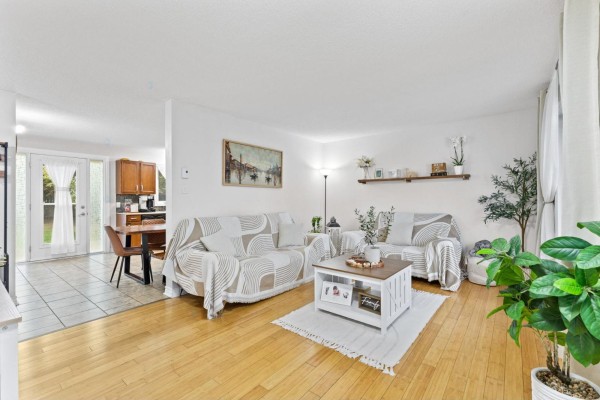 Living room with light wood floors, white walls, and two sofas covered in blankets. - 35 Rue De Candiac, Gatineau