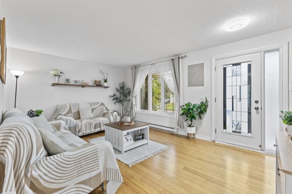 Living room featuring a large window, white walls, and a front door with decorative glass. - 35 Rue De Candiac, Gatineau