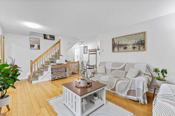 Living room with light wood floors, a staircase with wooden railings, and two sofas. - 35 Rue De Candiac, Gatineau