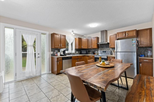 Kitchen with tiled floors, wooden cabinets, stainless steel appliances, and a live-edge dining table. - 35 Rue De Candiac, Gatineau