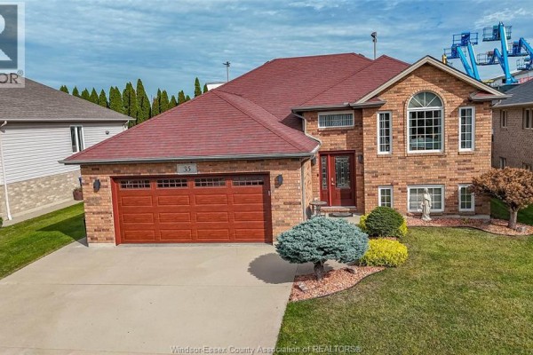 Front view of a brick house featuring a large red garage door and arched window. - 35 Sandy Lake, Leamington