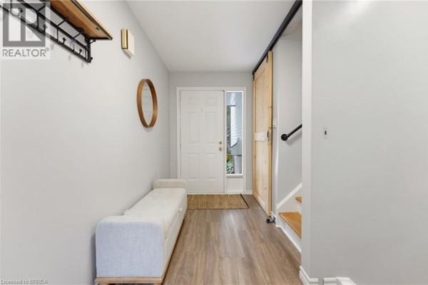 Hallway with light grey walls, wood-look flooring, a bench, and a wooden barn door. - 35 Scott Road, Cambridge
