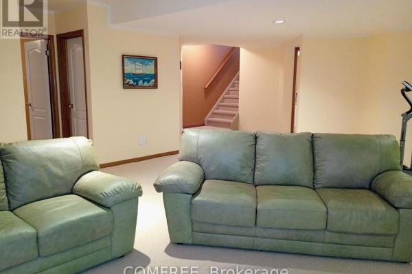 Green leather sofa and armchair in a living room with stairs - 35 Tanya Drive Southwest Middlesex