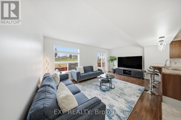 Living room with blue sectional, coffee table, TV & kitchen island - 35 Thames Way Hamilton