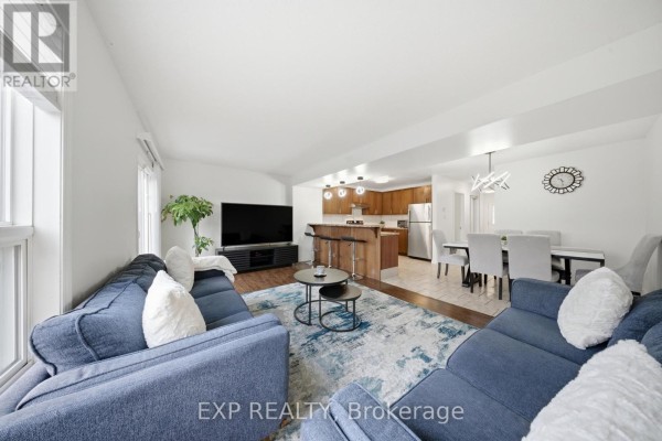 Living room with blue sectional, kitchen island, and dining area - 35 Thames Way Hamilton
