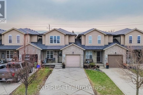 Aerial view of a row of townhouses with beige siding and attached garages. - 35 Thames Way, Hamilton