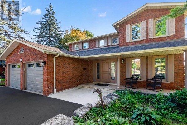 Front exterior of a red brick house featuring a covered porch and double garage. - 35 Yellow Pine Crescent, Vaughan