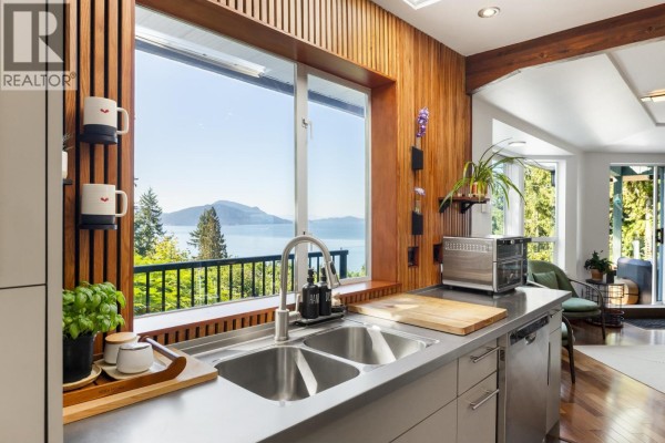 Kitchen sink and countertops with a large window overlooking a scenic ocean and tree view. - 350 Bayview Place, Lions Bay