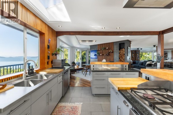 Spacious kitchen with island, stainless steel appliances, and open-plan view to dining and living areas. - 350 Bayview Place, Lions Bay