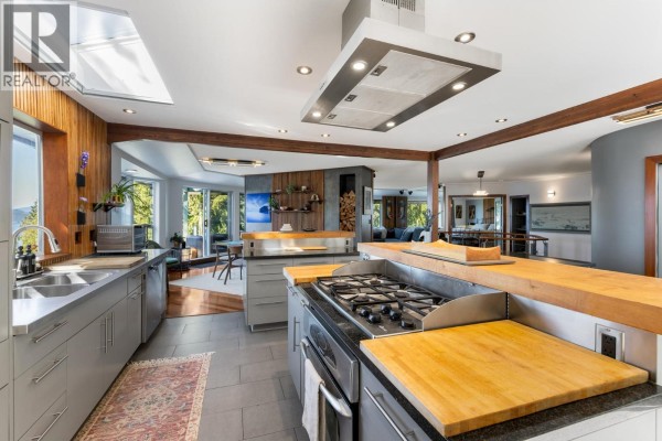 Kitchen island with butcher block, gas stove, and view into the open-concept living space. - 350 Bayview Place, Lions Bay