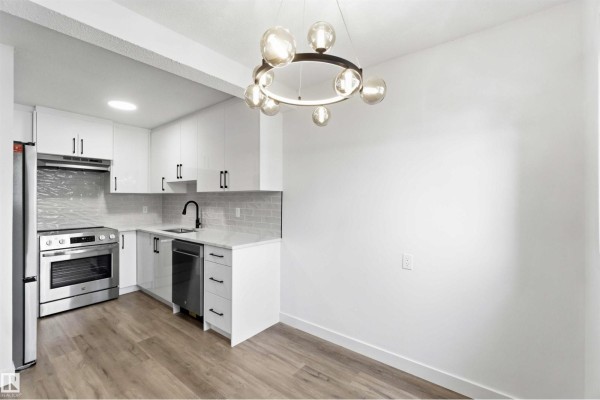 Backyard of townhouse with wooden fence and sliding glass doors, snow covered ground and trees. - 350 Clareview Rd Nw, Edmonton