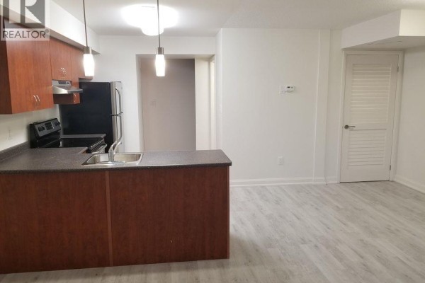 View of a compact kitchen area with dark wood cabinets and light gray flooring. - 350 Fisher Mills Road Unit# A-11, Cambridge