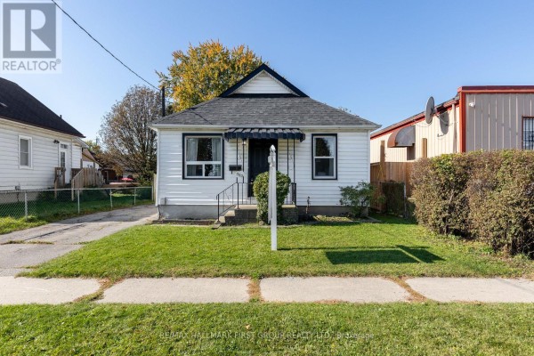Bedroom with hardwood floors, white walls, wood paneled wall, and a patterned curtain. - 350 Oshawa Boulevard S, Oshawa