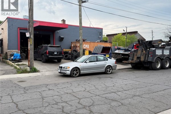 Parking lot filled with damaged and intact vehicles in front of a commercial building. - 350 Sherman Avenue N, Hamilton